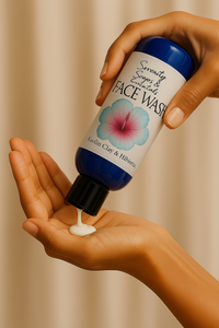 Hand holding a bottle of face wash with a floral label against a beige background